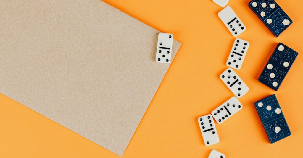 Top view of dominoes scattered on an orange background with empty space for text.