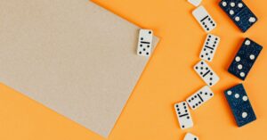 Top view of dominoes scattered on an orange background with empty space for text.